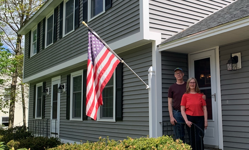 Homeowners in front of home with American flag