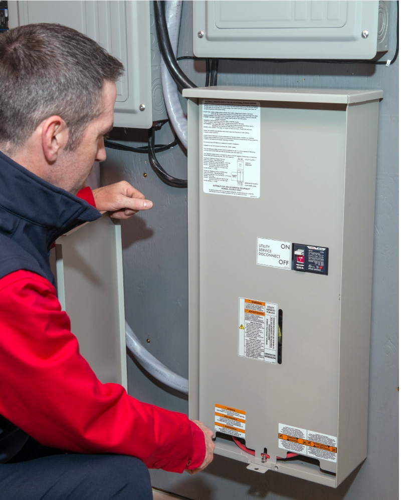 Technician kneeling at whole home standby generator panel