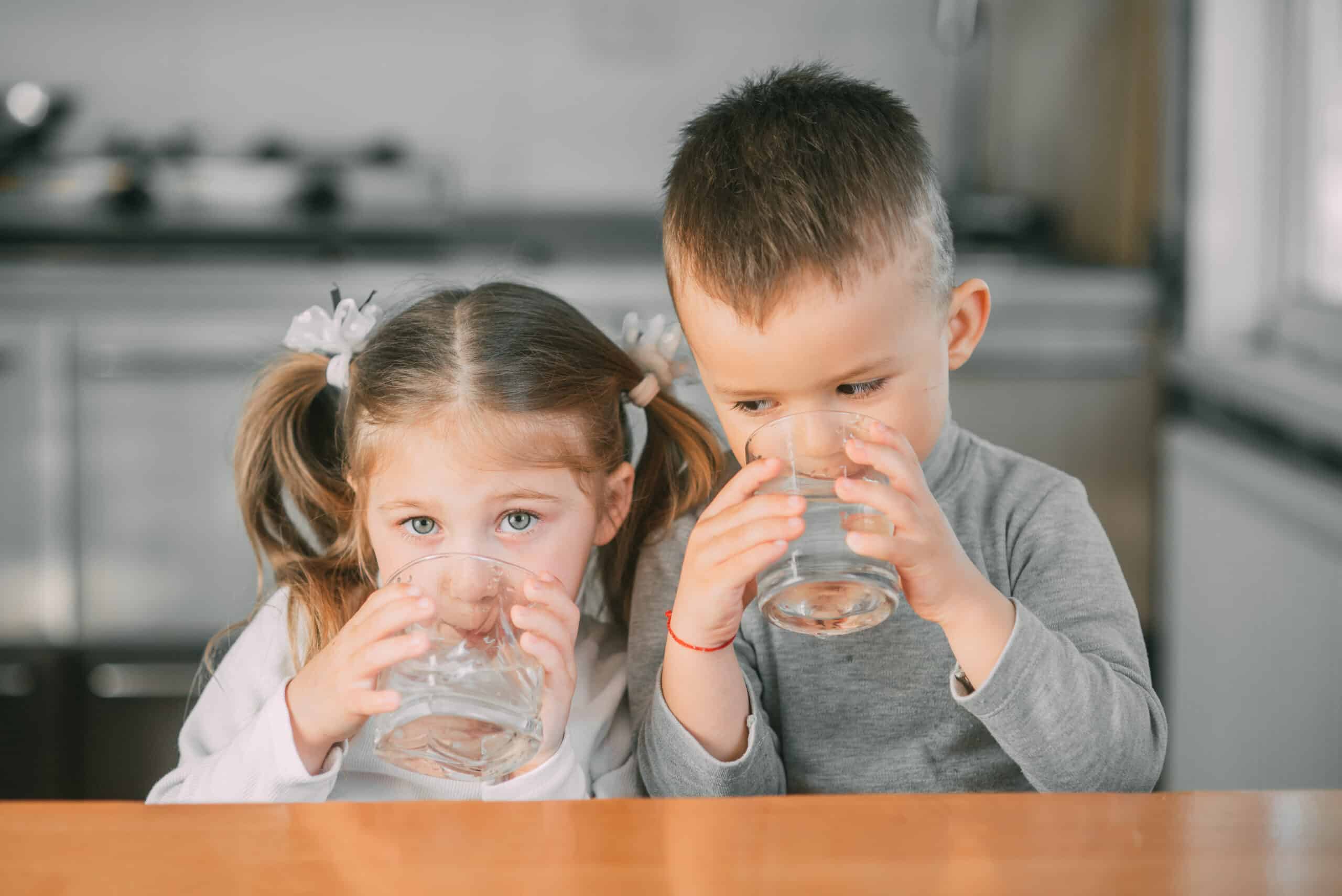 boy and girl in the kitchen drinking water