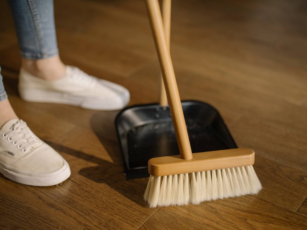 Person standing by dust pan and broom