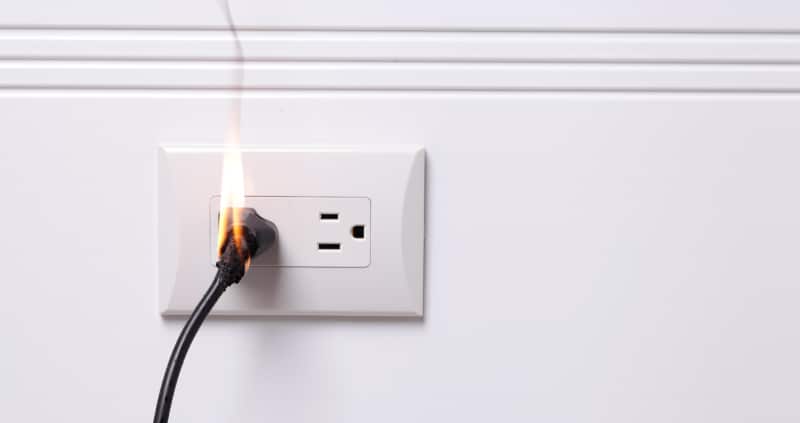 power cord plugged into electrical outlet. Outlet is on fire.