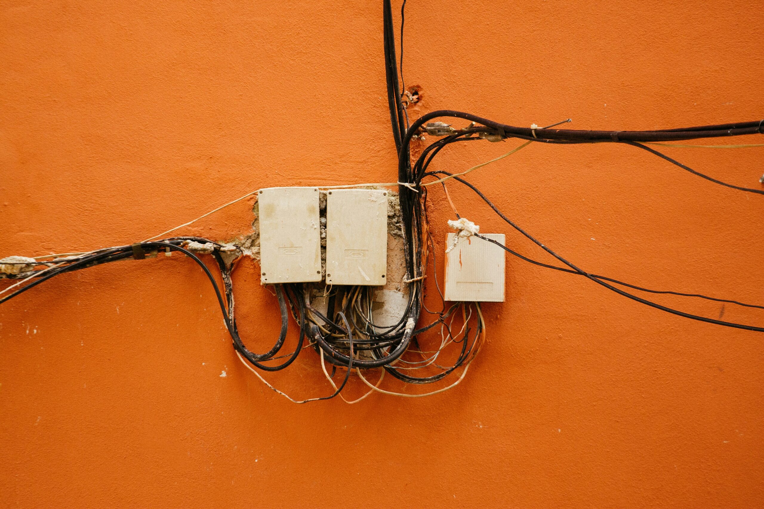 Exposed wiring and outdated electrical service boxes indicating need for home rewiring and safety inspection